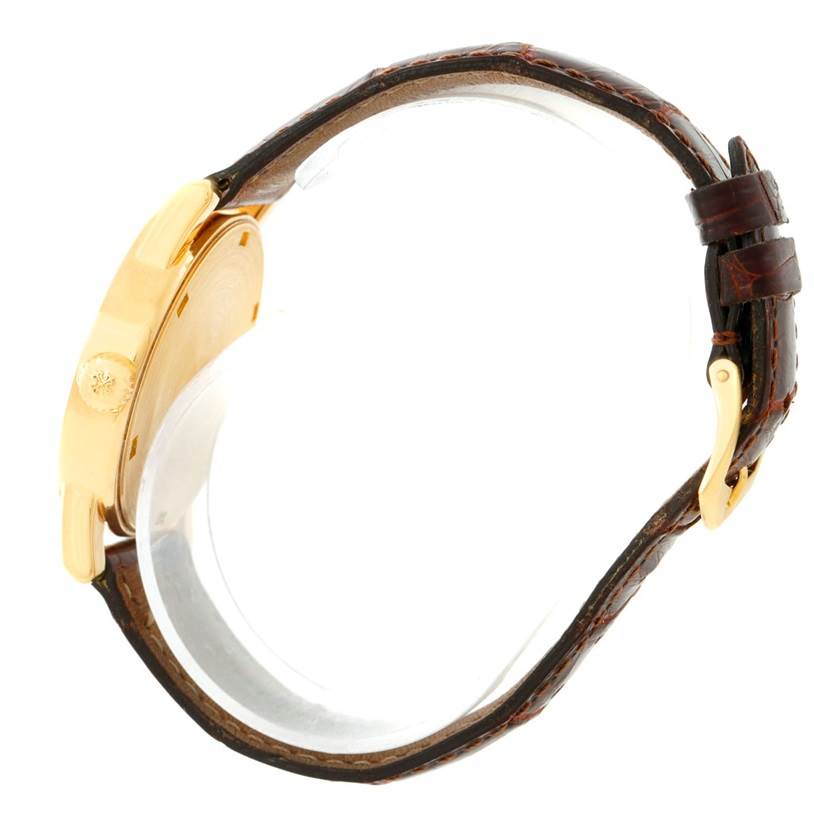 The image shows a side view of a Patek Philippe Calatrava 5012 Men
s Yellow Gold Beige Dial 5012 Men
s Yellow Gold Beige Dial watch, highlighting the case, crown, and leather strap.