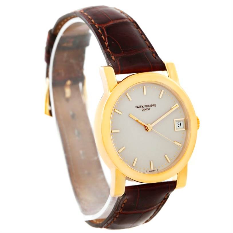 This image shows a Patek Philippe Calatrava 5012 Men
s Yellow Gold Beige Dial 5012 Men
s Yellow Gold Beige Dial watch at a slight angle highlighting the face, strap, and date display.