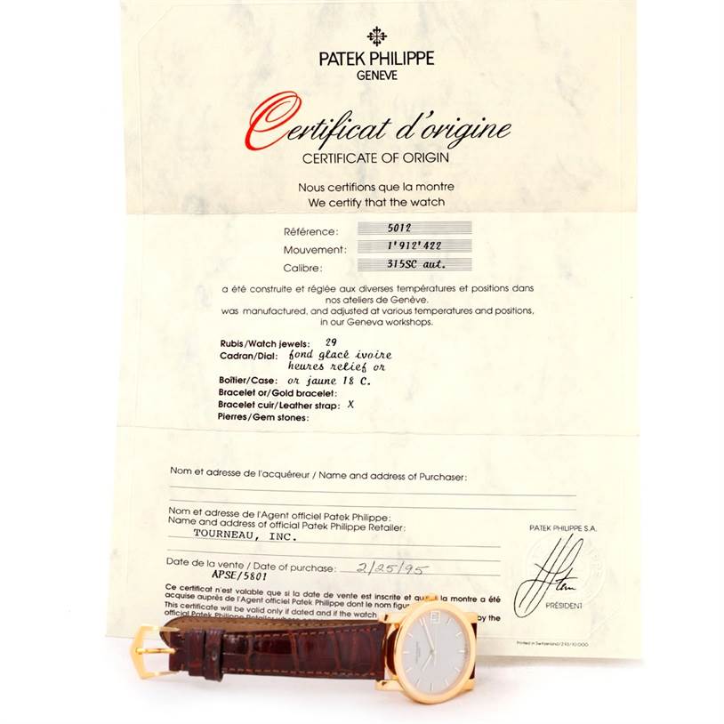 The image shows a Patek Philippe Calatrava 5012 Men
s Yellow Gold Beige Dial 5012 Men
s Yellow Gold Beige Dial watch with a leather strap, placed next to its certificate of origin, viewed from the front.