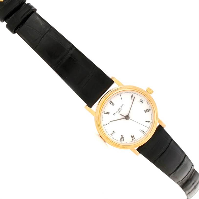 The Patek Philippe Calatrava 3802 Men's Yellow Gold White Dial 3802 Men's Yellow Gold White Dial watch is shown from a top-down angle, displaying its face, leather strap, and gold case.