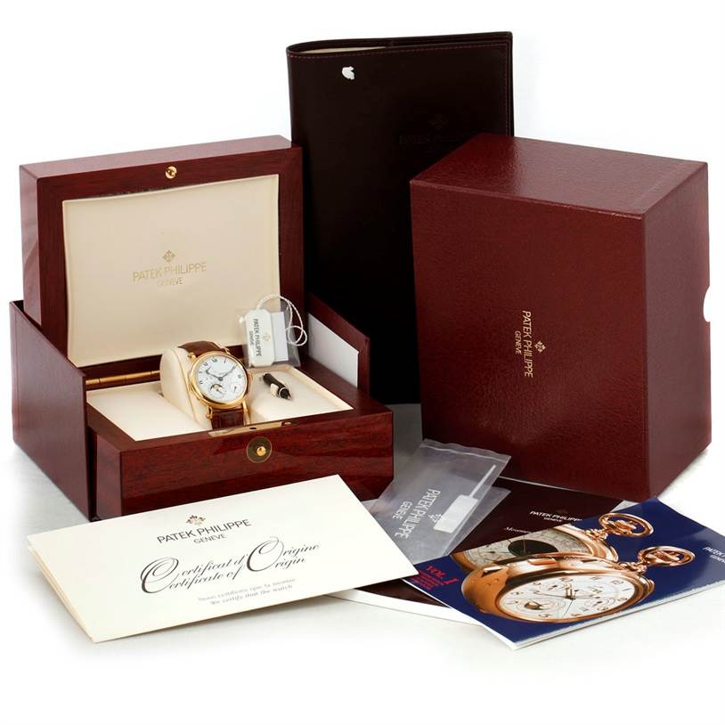 The image shows a Patek Philippe 5054 Men's Yellow Gold White Dial 5054 Men's Yellow Gold White Dial Power Reserve Moonphase Yellow Gold Watch 5054 with its box, papers, and accessories at an angle.