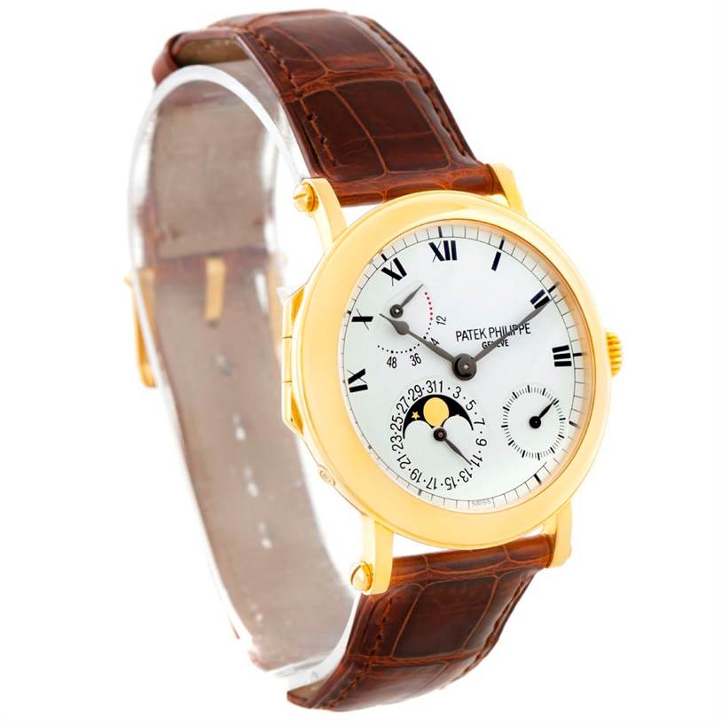 The Patek Philippe 5054 Men's Yellow Gold White Dial 5054 Men's Yellow Gold White Dial Power Reserve Moonphase Yellow Gold 5054 watch is shown from a front-left angle, highlighting the face and brown strap.