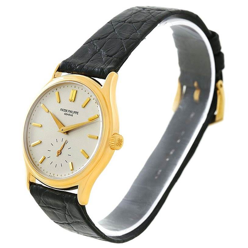 The Patek Philippe Calatrava 3923 Men's Yellow Gold Silver Dial 3923 Men's Yellow Gold Silver Dial watch is shown angled slightly to the left, highlighting the gold case, white dial, and black leather strap.