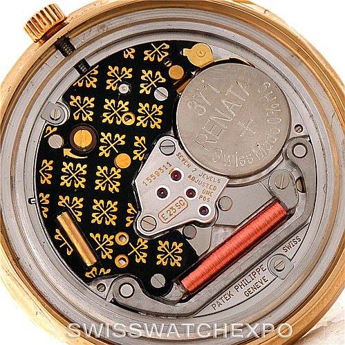 This view of the Patek Philippe Calatrava 3944 Men's Yellow Gold White Dial 3944 Men's Yellow Gold White Dial watch showcases its intricate movement, including gears, battery, and the embossed logos.