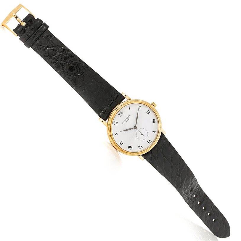 The image shows a top-view angle of a Patek Philippe Calatrava 3919 Men's Yellow Gold White Dial 3919 Men's Yellow Gold White Dial watch with a black leather strap and gold casing.