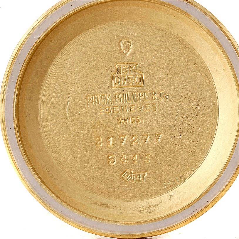 The image shows the inside back of the case for a vintage Patek Philippe watch, revealing engravings and hallmarks.
