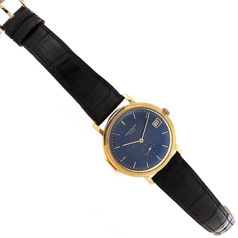 The image shows a Patek Philippe Vintage model watch from a top-down angle, displaying the face, black strap, and gold case.