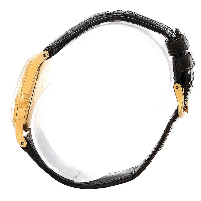 This side view shows the Patek Philippe Vintage watch
s gold case, crown, and black leather strap with a gold buckle.