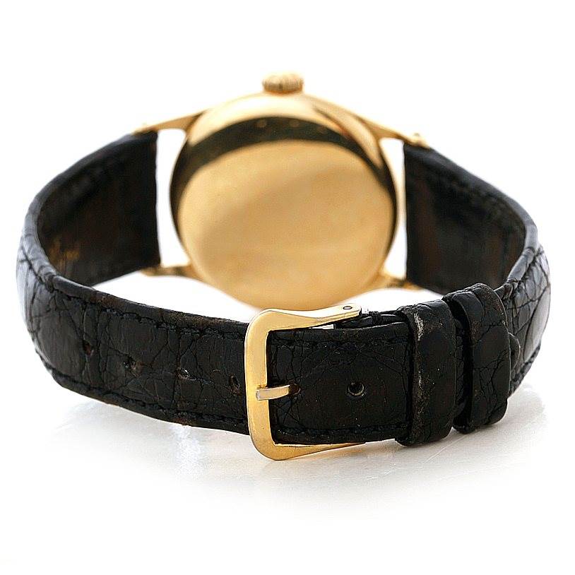 The image shows the back of a Vintage Patek Philippe watch with a gold case and black leather strap, focusing on the buckle.