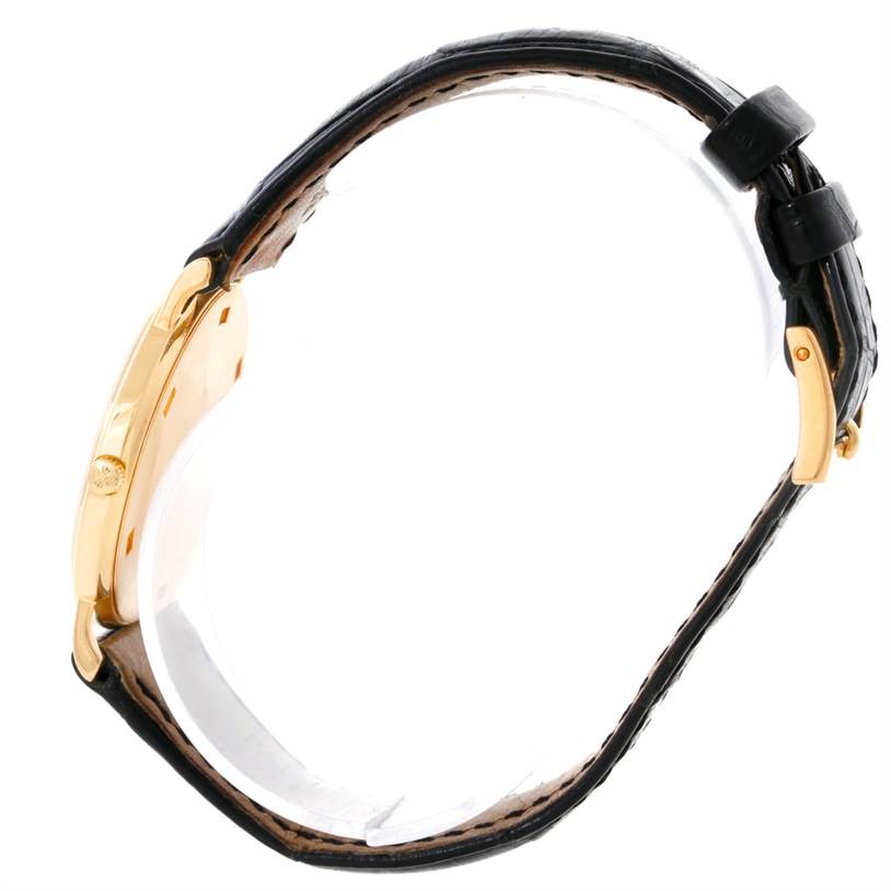 This side view of the Patek Philippe Calatrava 3520 Men's Yellow Gold White Dial 3520 Men's Yellow Gold White Dial watch shows the case, crown, and black leather strap.