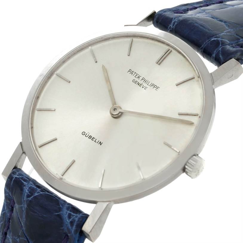 The image shows a close-up angle of a Vintage Patek Philippe watch, highlighting the dial, hands, and part of the blue leather strap.