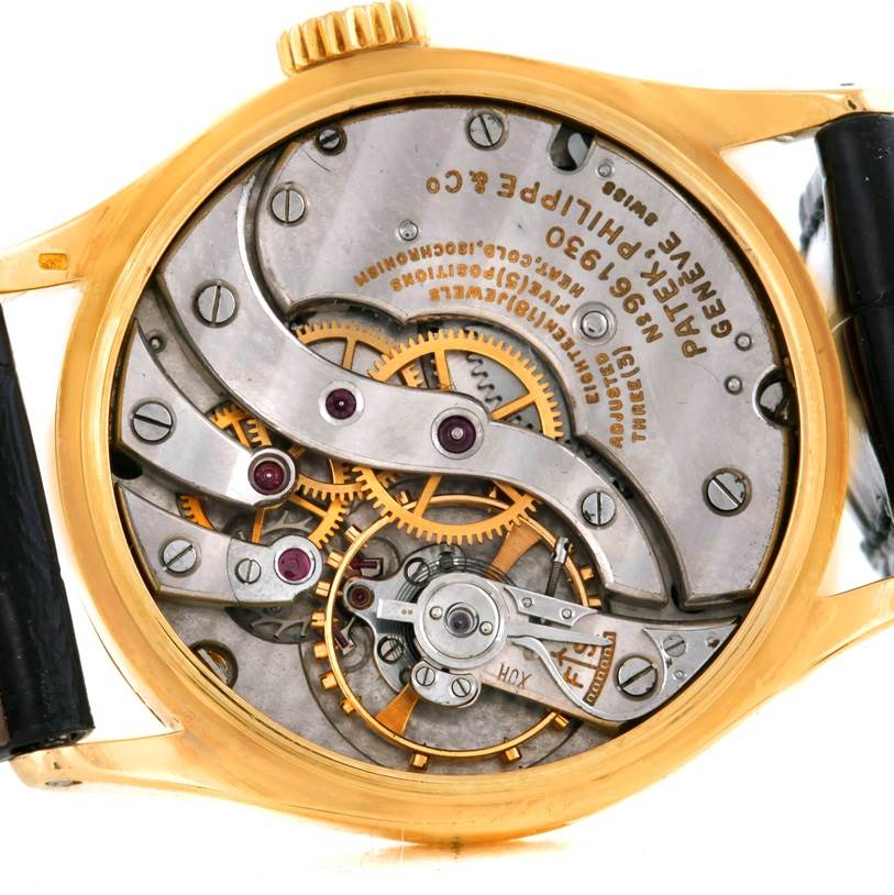 This image showcases the inner workings of a Vintage Patek Philippe watch, highlighting its intricate gears and movement from a back angle.