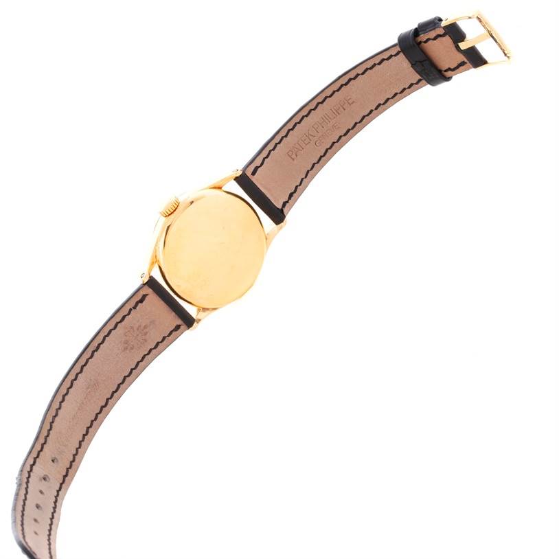 The image shows the back view of a vintage Patek Philippe watch, displaying the gold case and leather strap.