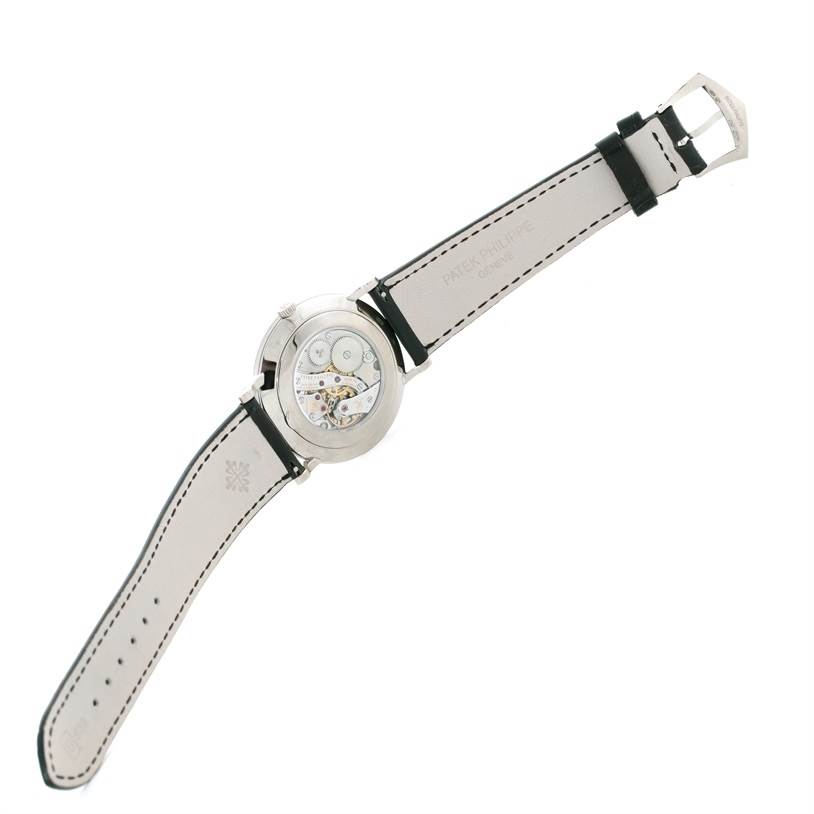 The image shows the back view of a Patek Philippe Calatrava 5119G Men's White Gold White Dial 5119G Men's White Gold White Dial watch, featuring its exposed movement and leather strap.
