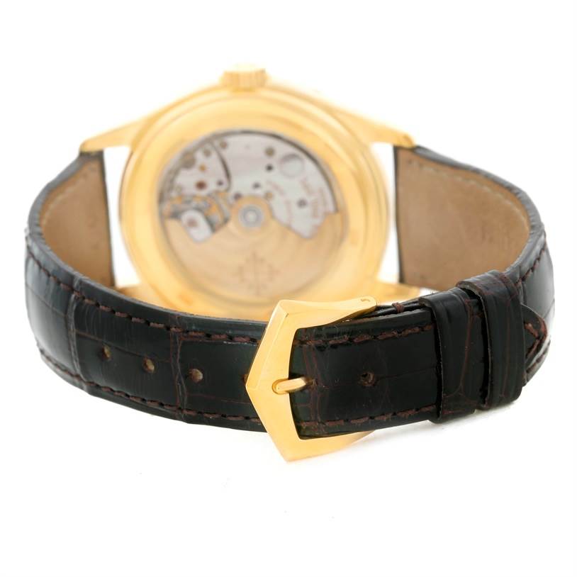 The image shows the back view of a Patek Philippe Complications 5035R Men
s Yellow Gold Silver Dial 5035R Men
s Yellow Gold Silver Dial watch, highlighting the movement through the transparent case back and the leather strap with buckle.