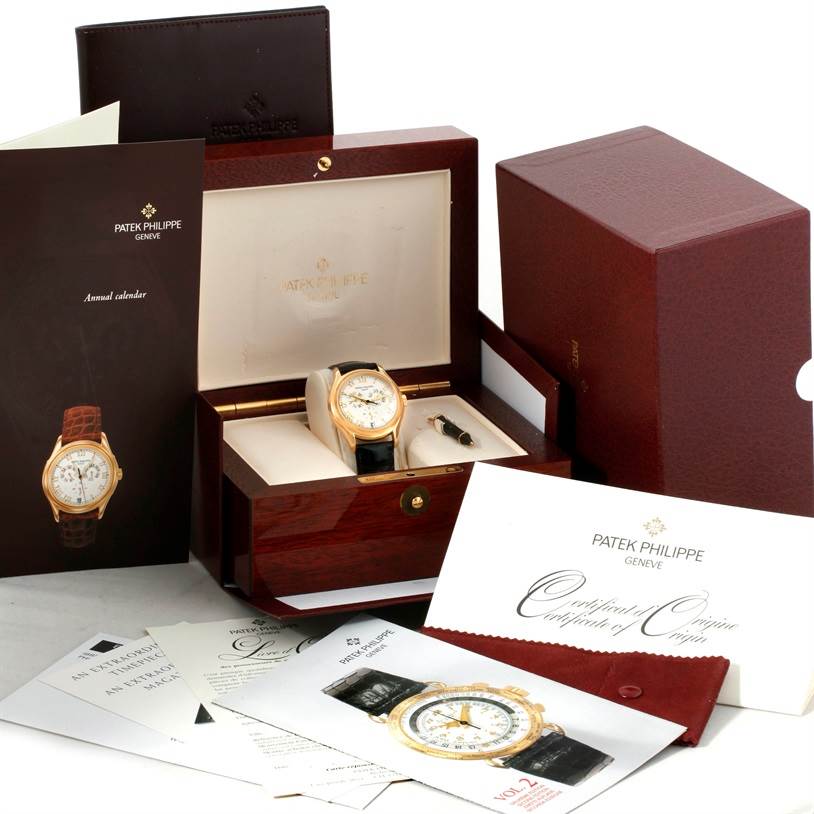 The Patek Philippe Complications 5035R Men
s Yellow Gold Silver Dial 5035R Men
s Yellow Gold Silver Dial watch is displayed in its box, along with manuals, certificates, and additional accessories.
