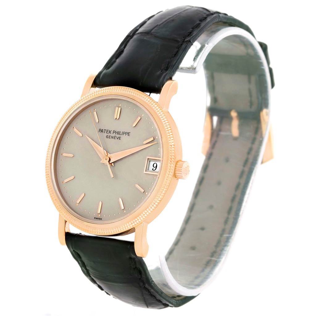 The Patek Philippe Calatrava 3802R Men's Rose Gold Beige Dial 3802R Men's Rose Gold Beige Dial watch is shown at an angled view, highlighting its face, black strap, and gold case with a date display.