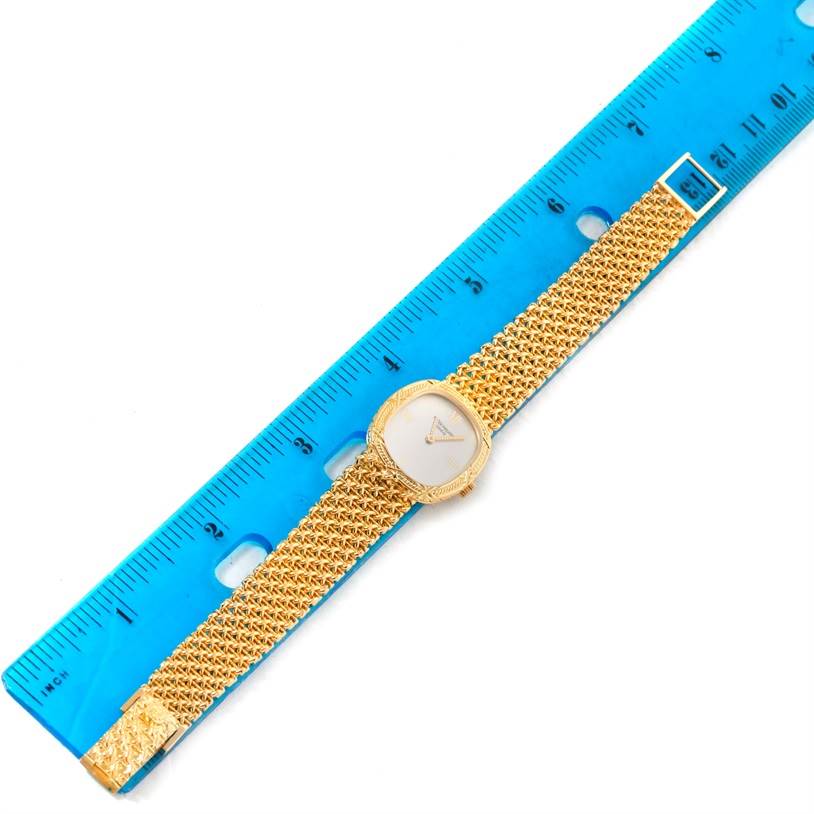 The image shows an aerial view of a Vintage Patek Philippe watch with a gold mesh band placed next to a blue ruler.