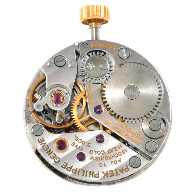 This image shows the internal mechanism of a Vintage Patek Philippe watch, highlighting its gears, cogs, and jewel bearings.