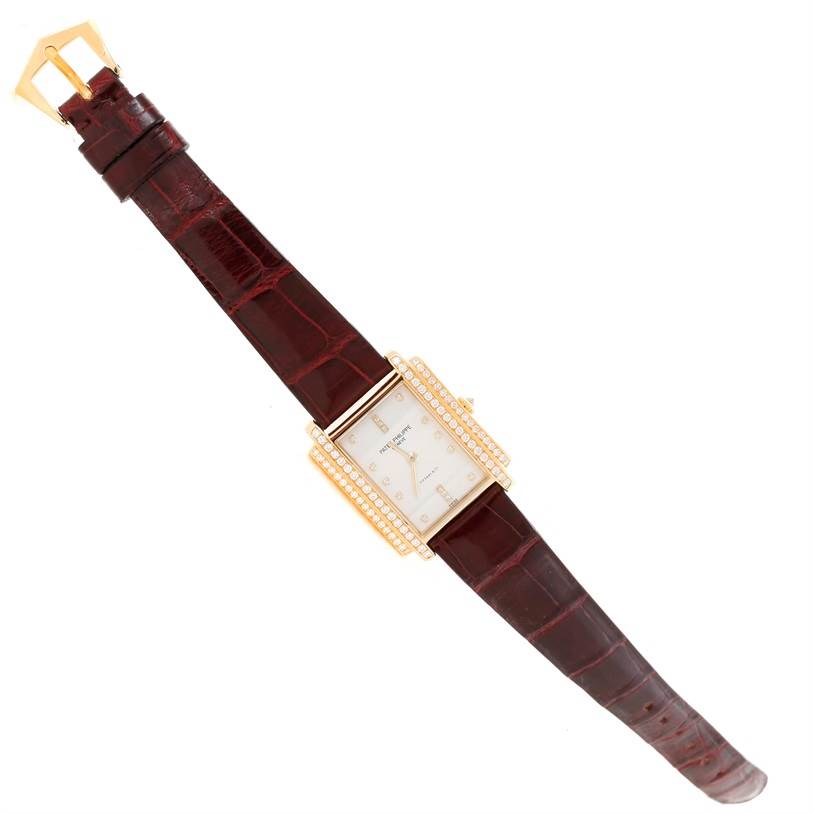 The image shows a top view of a Patek Philippe Gondolo 4825/100 Women's Yellow Gold White Dial 4825/100 Women's Yellow Gold White Dial watch, featuring its dial, strap, and buckle.