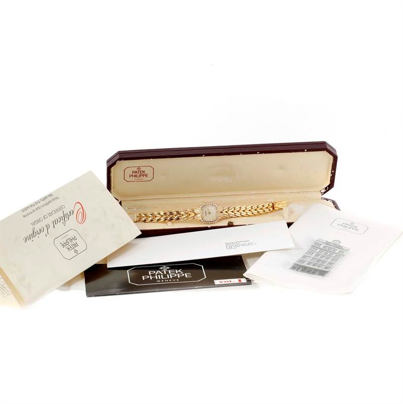 The image shows a La Flamme model by Patek Philippe in its open case, alongside various documentation and booklets.