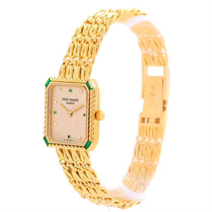 The image shows a front and side angle of the Patek Philippe 4667 Women's Yellow Gold Beige Dial 4667 Women's Yellow Gold Beige Dial 4667 model, highlighting its gold bracelet, diamond markers, and emerald accents.
