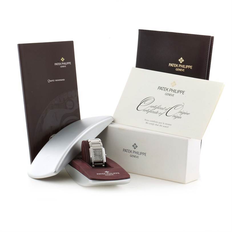 The image shows a Patek Philippe Twenty-4 4910/10A-010 Women's Stainless Steel Grey Dial 4910/10A-010 Women's Stainless Steel Grey Dial watch, its box, warranty papers, and instruction booklet from a frontal angle.