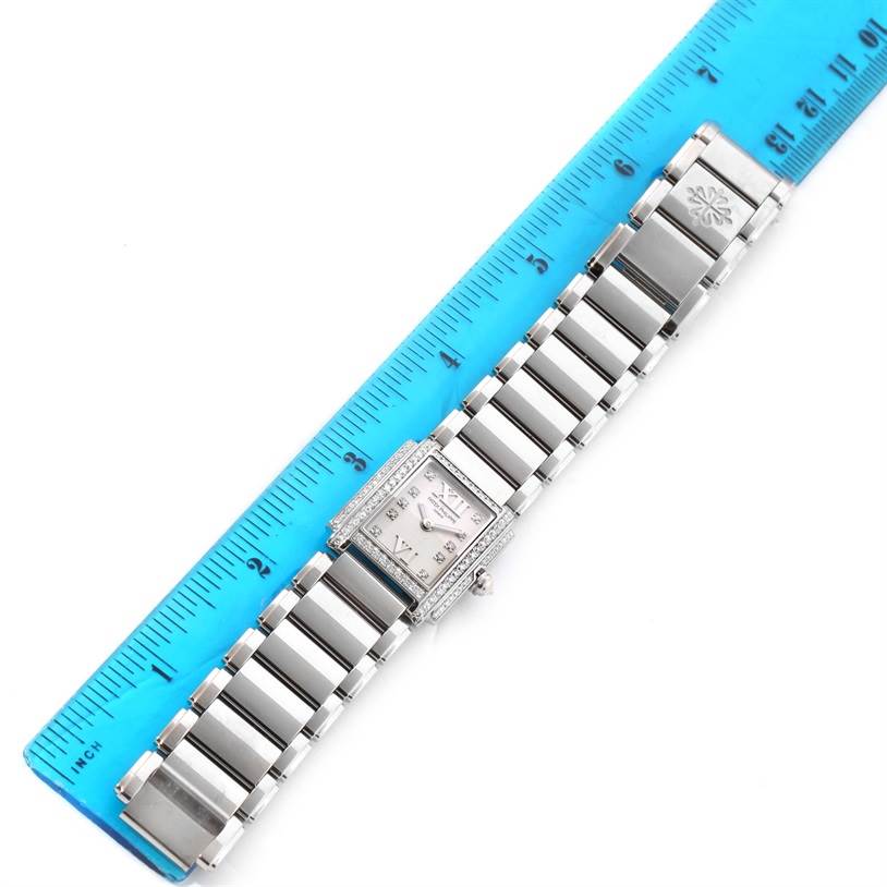 The Patek Philippe Twenty-4 4908/200G-011 Women's White Gold Silver Dial 4908/200G-011 Women's White Gold Silver Dial watch is shown from a top-down angle, aligned next to a blue ruler for size reference.