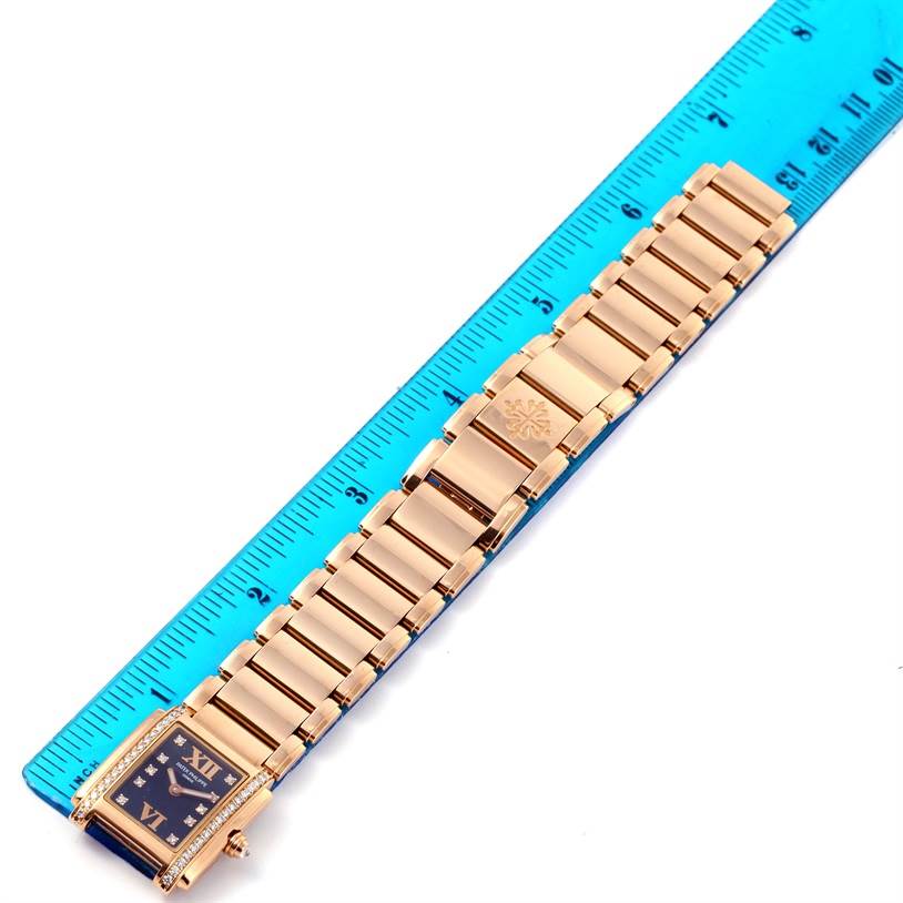 The image shows a Patek Philippe Twenty-4 4908/11R Women's Rose Gold Black Dial 4908/11R Women's Rose Gold Black Dial model watch laid flat next to a ruler, displaying the watch face, bracelet, and clasp.