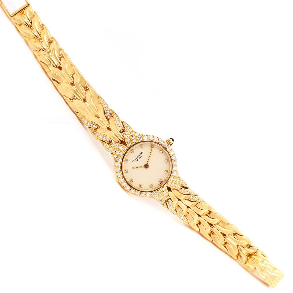 The image shows a top view of a Patek Philippe La Flamme  4816 Women's Yellow Gold Beige Dial 4816 Women's Yellow Gold Beige Dialwatch, featuring a gold bracelet and diamond accents.