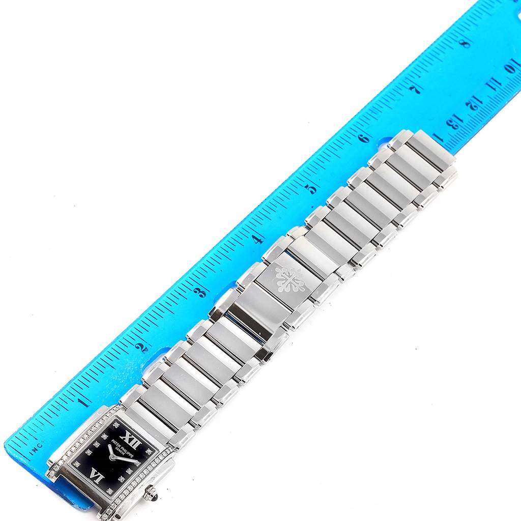 The image shows a Patek Philippe Twenty-4 4910-10A-001 Women
s Stainless Steel Black Dial 4910-10A-001 Women
s Stainless Steel Black Dial watch laid flat next to a ruler, displaying its face and bracelet links.