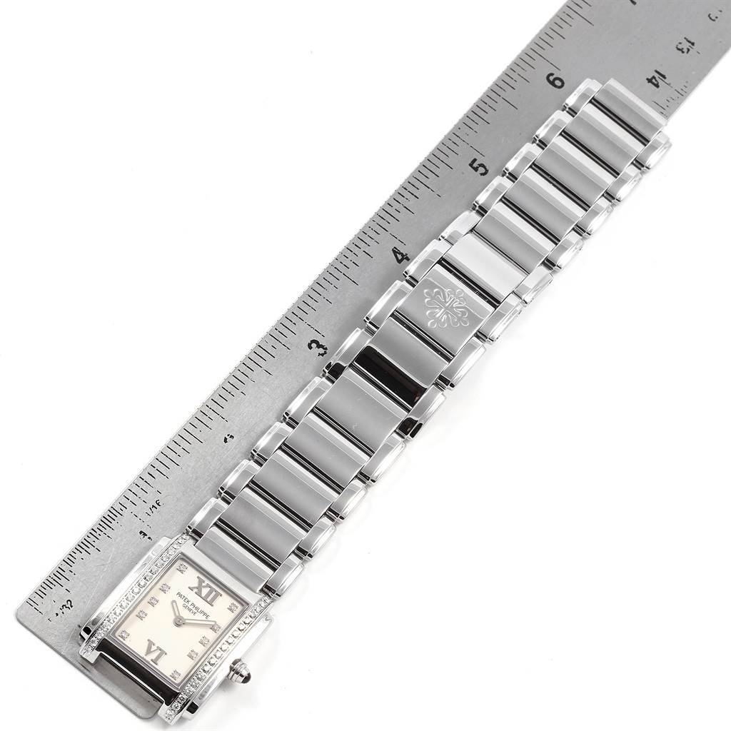 The image shows the face and bracelet of a Patek Philippe Twenty-4 4910/10A-010 Women's Stainless Steel Silver Dial 4910/10A-010 Women's Stainless Steel Silver Dial model watch placed beside a ruler for scale.