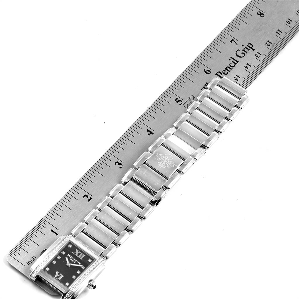 The image shows a top-down view of a Patek Philippe Twenty-4 4910-10A-001 Women's Stainless Steel Black Dial 4910-10A-001 Women's Stainless Steel Black Dial watch, highlighting the face, bracelet, and a ruler for scale.