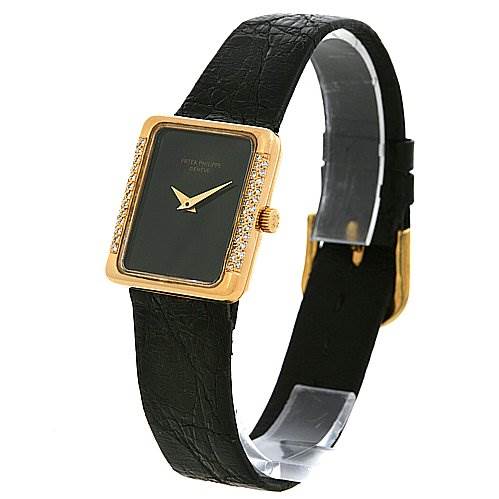 This image shows a side-angle view of a Vintage Patek Philippe watch, highlighting its black leather strap, rectangular gold frame, and minimalist dial.