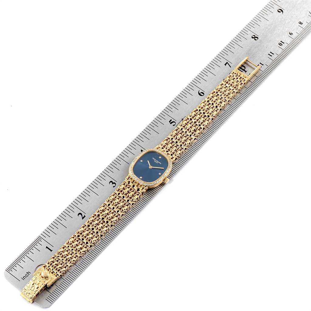 The image displays the entire Patek Philippe Golden Ellipse 4698/1 Women's Yellow Gold Blue Dial 4698/1 Women's Yellow Gold Blue Dial watch laid flat on a ruler, showcasing the face, strap, and buckle.