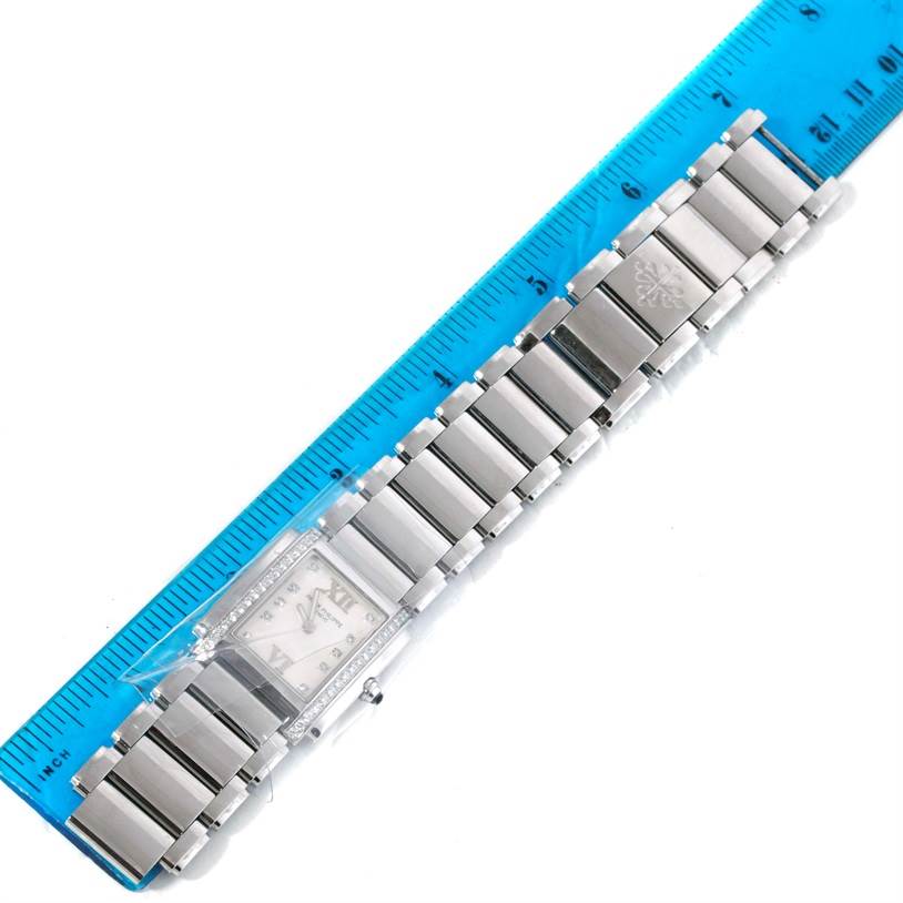 The image shows a Patek Philippe Twenty-4 4910/10A-011 Women
s Stainless Steel Silver Dial 4910/10A-011 Women
s Stainless Steel Silver Dial watch laying flat with the full bracelet visible and placed next to a ruler for size reference.