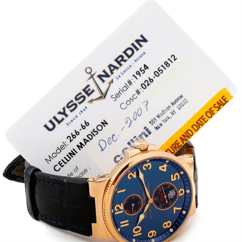 The image shows a side angle of a Ulysse Nardin Marine 266-66 Men's Rose Gold Blue Dial 266-66 Men's Rose Gold Blue Dial model watch alongside its certificate of sale.