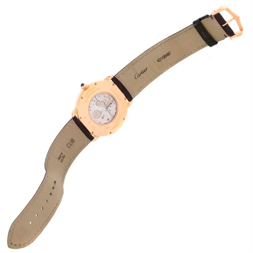 The image shows the back side of a Cartier Ronde W6800251 Men
s Rose Gold Silver Dial W6800251 Men
s Rose Gold Silver Dial watch, along with its open leather strap and the exposed movement.