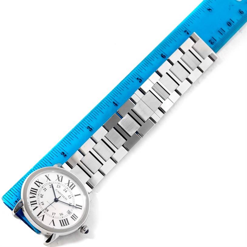 The image shows the Cartier Ronde W6701011 Men
s Stainless Steel Silver Dial W6701011 Men
s Stainless Steel Silver Dial watch from an overhead angle alongside a blue ruler, highlighting the watch
s face and metal band.