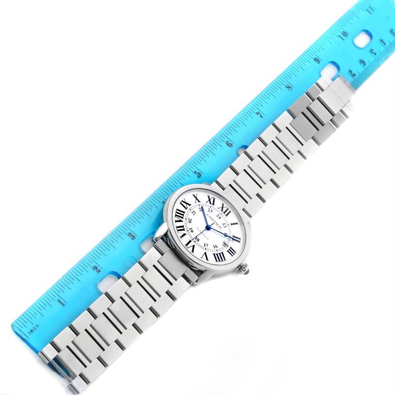 The Cartier Ronde W6701011 Men's Stainless Steel Silver Dial W6701011 Men's Stainless Steel Silver Dial watch is shown from an overhead angle with its bracelet extended alongside a blue ruler.