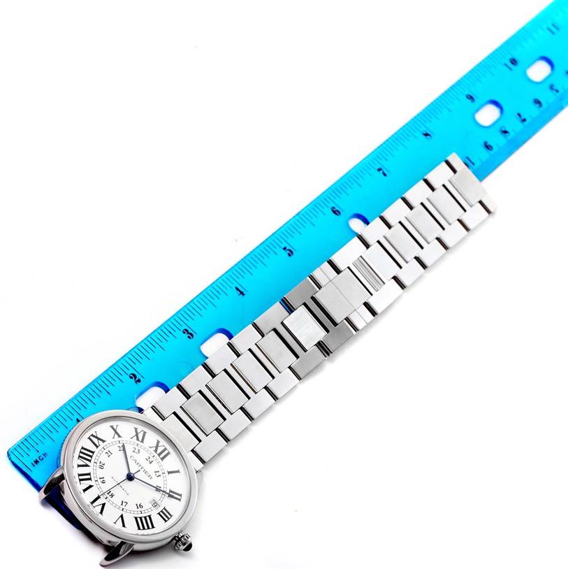 The image shows a Cartier Ronde W6701011 Men
s Stainless Steel Silver Dial W6701011 Men
s Stainless Steel Silver Dial watch with its face and stainless steel bracelet alongside a blue ruler for measurement.