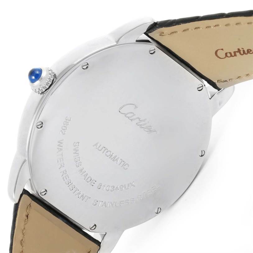 The image shows the back case and part of the strap of a Ronde model by Cartier, along with the crown featuring a blue gemstone.