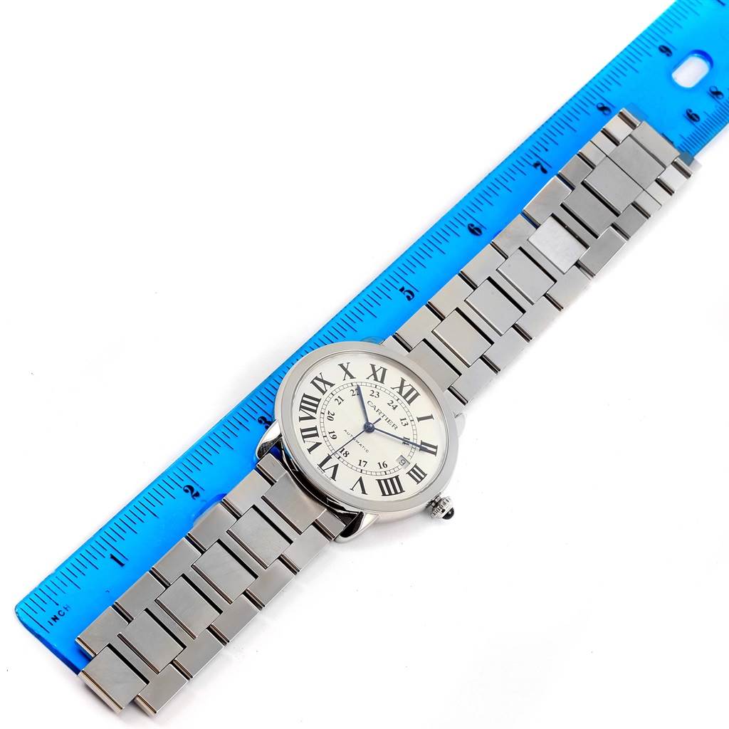 The Cartier Ronde W6701011 Men
s Stainless Steel Silver Dial W6701011 Men
s Stainless Steel Silver Dial watch is shown lying flat with its bracelet extended alongside a blue ruler for scale.