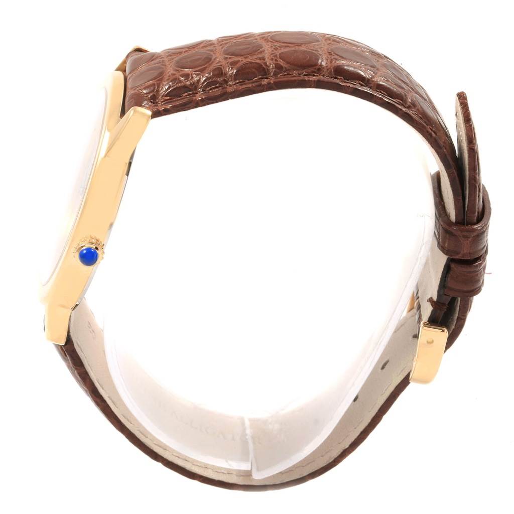 This image shows a side view of the Cartier Ronde W6700455 Men's Steel and Gold (two tone) Silver Dial W6700455 Men's Steel and Gold (two tone) Silver Dial watch, highlighting its gold case, blue gemstone crown, and brown leather strap.