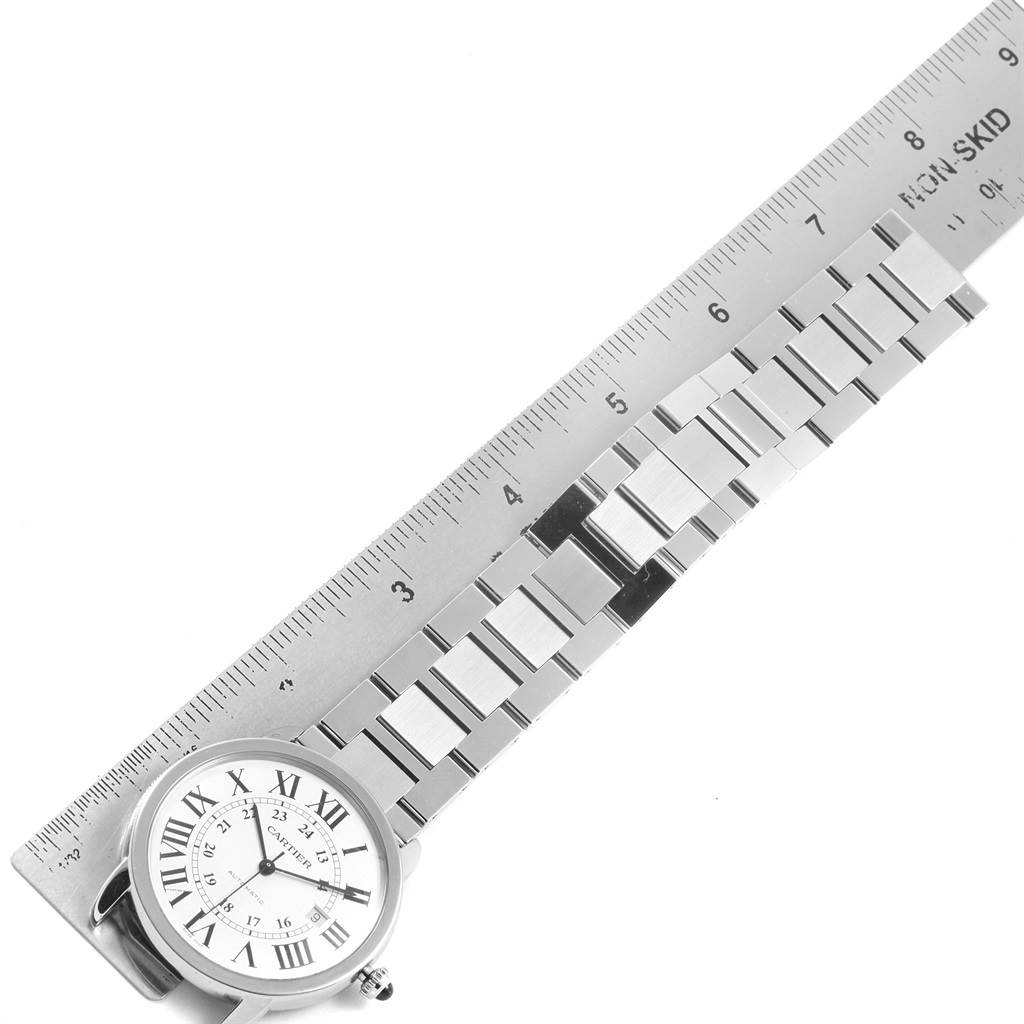 The image shows the face and metal bracelet of the Ronde model watch by Cartier alongside a ruler.