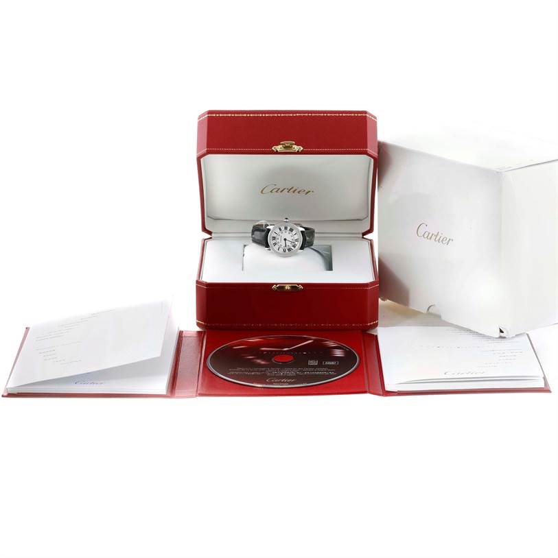 The image shows a Cartier Ronde W6700155 Women
s Stainless Steel Silver Dial W6700155 Women
s Stainless Steel Silver Dial watch in its open case, with accompanying booklets and a CD displayed around it.