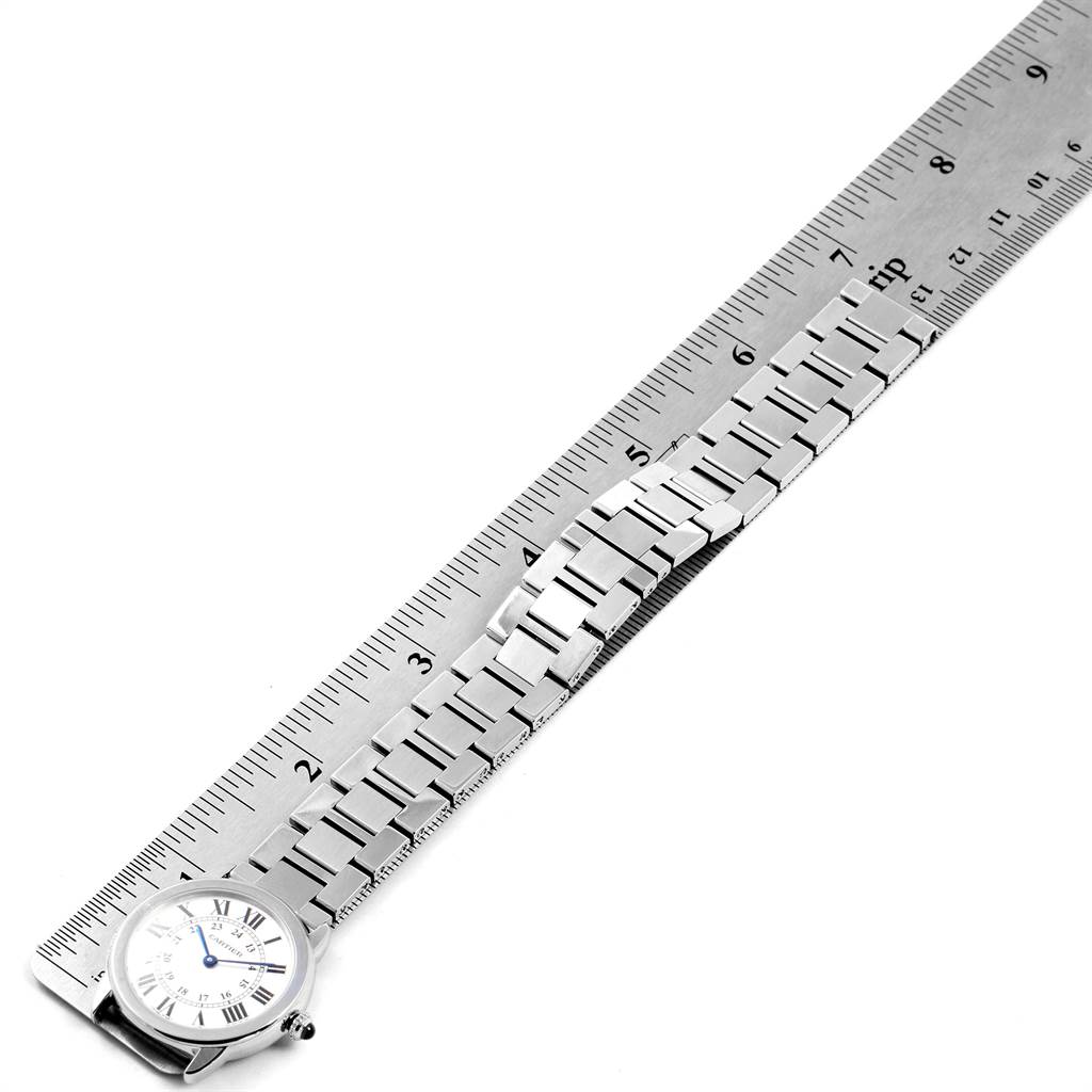This image shows the entire Ronde model by Cartier watch lying flat, with the face and the stainless steel bracelet visible, next to a ruler.