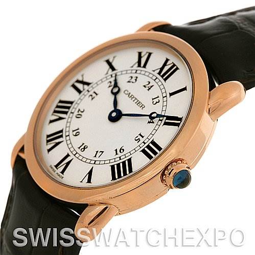 The image shows a close-up side angle of a Cartier Ronde W6800151 Women
s Rose Gold Silver Dial W6800151 Women
s Rose Gold Silver Dial model watch, highlighting its white dial, Roman numerals, and the crown with a blue gemstone.