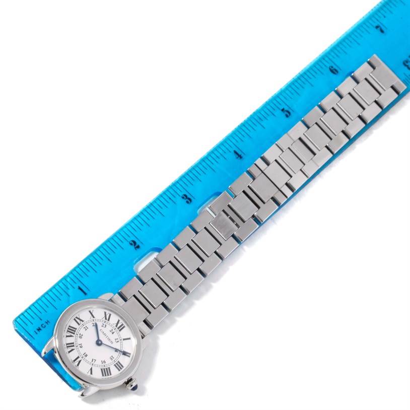 The image shows a Cartier Ronde W6701004 Women
s Stainless Steel Silver Dial W6701004 Women
s Stainless Steel Silver Dial watch laid flat alongside a ruler, highlighting the watch
s face and metal bracelet.