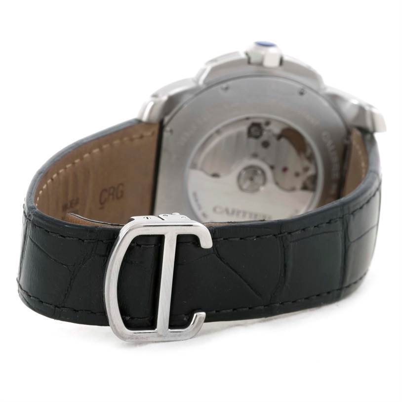 The image shows the back side of a Calibre de Cartier watch by Cartier, featuring its movement and a black leather strap with a "C" buckle.